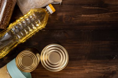 Mısır gevrekleri, çeşitli ürünler, konserve yiyecekler, makarna ve sabun ahşap bir arka planda yazılı. Koronavirüs salgını sırasında insani yardım. Çürümez gıda stoğu.