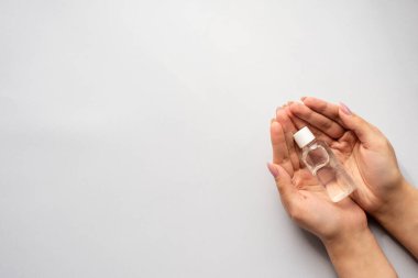 Coronavirus salgını koruması. Kızın elinde mavi bir arka planda antiseptik var..