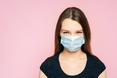 Pembe arka planda, koruyucu mavi maskeli genç sarışın kız. Reklam için şablon ve metin için yer. Kopyalama alanı.