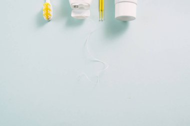 Sarı diş fırçası, iplik, diş macunu ve pamuk tomurcukları mavi arka planda reklamınız için bir yer. Diş bakımı ve diş temizliği kavramı.