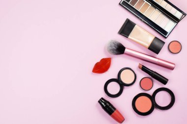 Kozmetik ürünleri pembe arka planda. Makyaj yakın görüşte. Arka planda bir kadın için çok fazla makyaj malzemesi var..