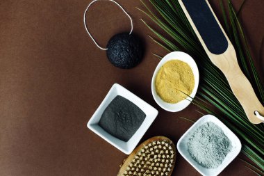 Clay kahverengi arka planda bir kaşıkta. Kahverengi arka planda gevşek maddeler ve bir fırça var.