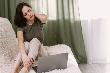 Boyun ağrısı çeken, gerinen bir iş kadını. Yorgun bir kadın masaj yapıyor, boynu ağrıyor, kasları kasılmış, bilgisayar işinden yorgun düşmüş. Freelancer evde, kanepede çalışmaktan yoruldu..