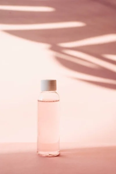 带粉色玫瑰水的塑料瓶 背景为棕榈叶的热带阴影 透明的滋润和清洁肌肤的润肤剂和润肤剂 胶水或洁净泡沫 — 图库照片