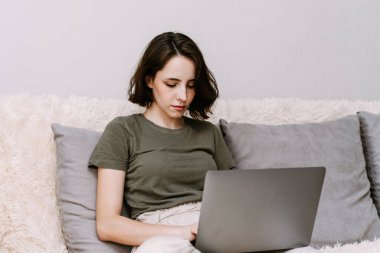 Genç bir bayan dizüstü bilgisayar kullanıyor, evdeki müşteriyle internet üzerinden iletişim kuruyor. Konforlu ofis işyeri, uzak çalışma karantina ve kendini izole etme konsepti..