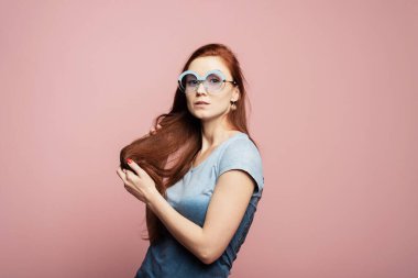 Pembe arka planda neşeli yüz ifadesiyle fevkalade bir kadın modeli. Güneş gözlüklü genç bir kadının portresi pembe duvarın önüne atlıyor..