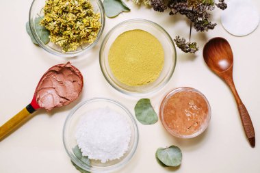 Bir buket kurutulmuş çiçek, ahşap kaşık ve cam kaseler doğal ürünlerle karıştırılıp doğal maskeler ve kremler yaratmak için.