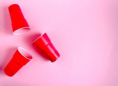 Pembe izole arkaplanda kırmızı plastik bardak