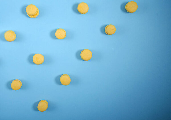Yellow macarons lie in rows diagonally against a blue background