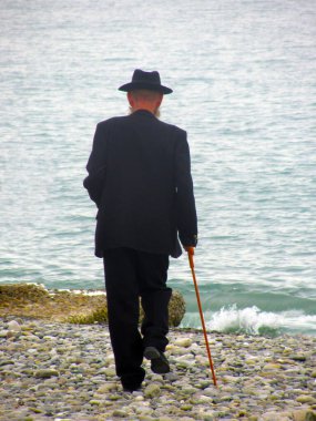 Siyah takım elbiseli, bastonlu yaşlı bir adam çakıl taşı plajı boyunca denize doğru yürüyor. Yalnızlık, emeklilik, akrabalarla ilişkiler, hastalık, hastalık, hastalık, hastalık, ölüm kavramı.