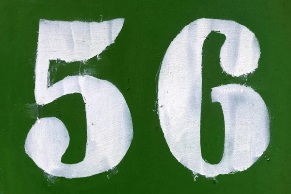 Number 56 white stencil digits painted on green metal surface ...