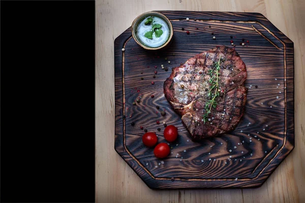 steak on a serving board with 3 cherry and sauce and black frame