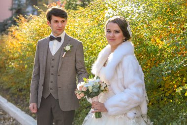 Güzel çalıların arasında el ele tutuşan evli bir çift.