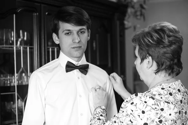 Mama pomaga synowi i panu młodemu ubrać się w garnitur ślubny. Pan młody i mama przygotowują się do ślubu. — Zdjęcie stockowe