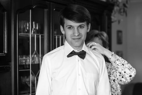 Mamá ayuda a su hijo y su novio a vestirse con un traje de novia. Novio y mamá se están preparando para la boda . — Foto de Stock