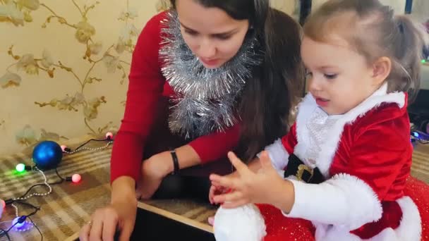 Mamá con hija en la pizarra dibuja atributos navideños. Mamá y su hija están dibujando un árbol de Navidad. Tema de Navidad: mamá e hija pintan Navidad en un ambiente festivo hogareño . — Vídeo de stock