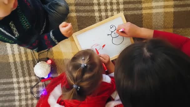 Kurulda kızı olan anne Noel özelliklerini çiziyor. Anne ve kızı bir Noel ağacı çiziyorlar. Noel teması: Anne ve kızı Noel 'i sade bir şenlik ortamında boyuyor.. — Stok video