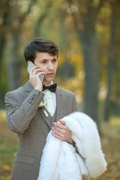 Pan młody rozmawia przez telefon w jesiennym parku — Zdjęcie stockowe