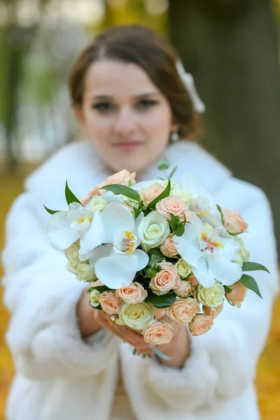 Наречена з букетом квітів в осінньому парку в білій шубці — стокове фото