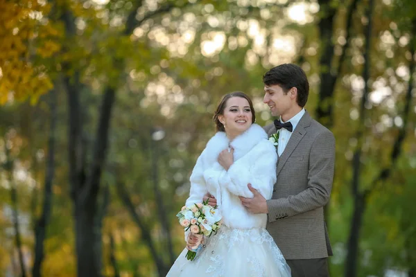 De bruid en bruidegom kussen in het herfstpark. — Stockfoto