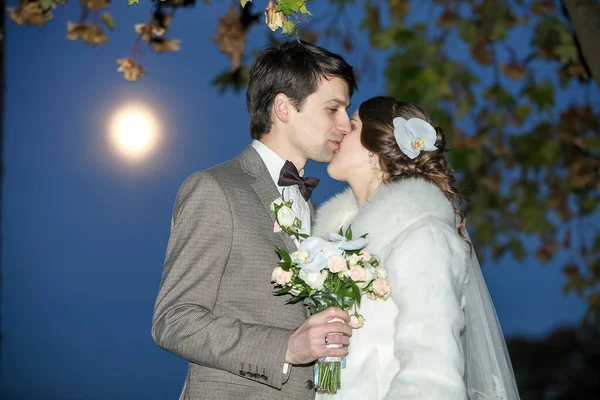 Zitting van de mysterieuze en romantische, de bruid en bruidegom onder de maan. Hugs samen. Man en vrouw, trouwjurk. — Stockfoto