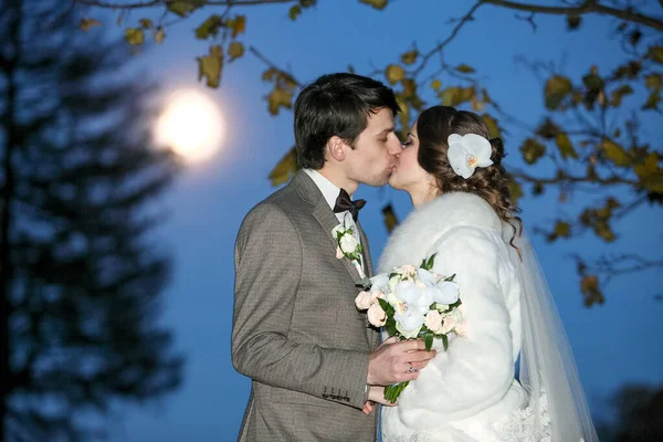 Zitting van de mysterieuze en romantische, de bruid en bruidegom onder de maan. Hugs samen. Man en vrouw, trouwjurk. — Stockfoto