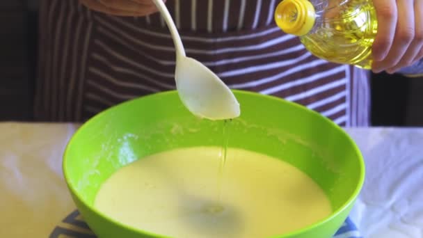 Gros plan Le mouvement lent d'une main féminine ajoute de l'huile de tournesol à la pâte dans un bol vert dans la cuisine de la maison. Crêpes de cuisson — Video