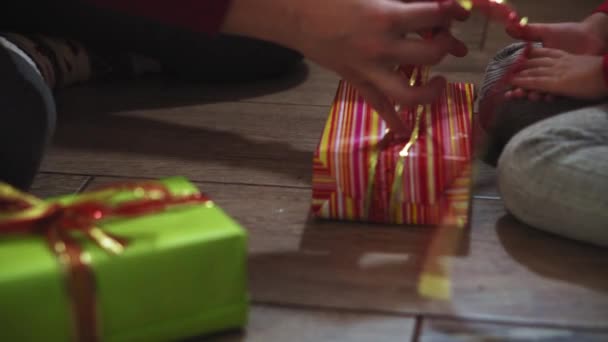 Tett på kvinne- og jentehender pakker gaver i esker i jule- og nyttårsfarger . – stockvideo