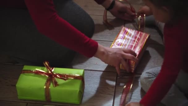Крупним планом жінка і дівчина руки упаковки подарунків в коробки в різдвяні і новорічні кольори . — стокове відео