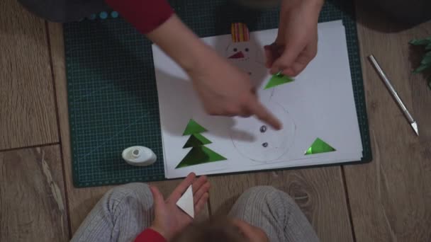 Primer plano de las manos de mujer y niña haciendo muñeco de nieve con apliques de papel . — Vídeos de Stock