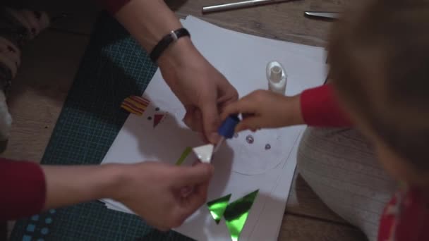 Nahaufnahme von Frau und kleinen Mädchenhänden, die mit Papierapplikationen Schneemänner basteln. — Stockvideo