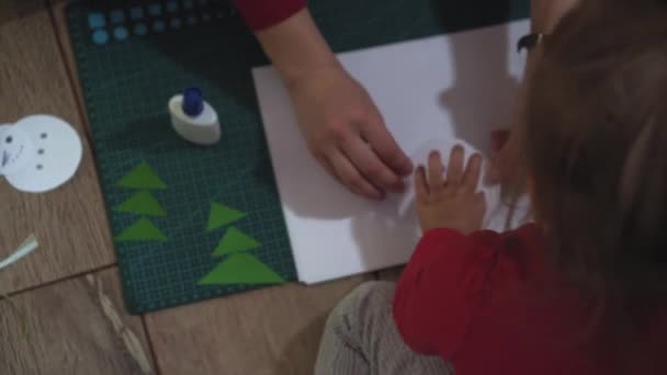 Close up de mulher e meninas mãos fazendo boneco de neve com papel applique . — Vídeo de Stock