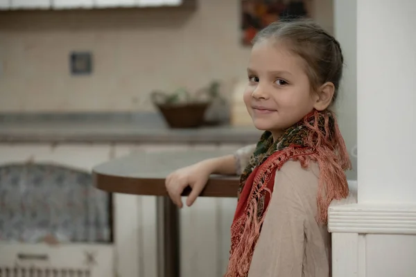 Une fille blonde foncée dans une robe beige et une écharpe colorée qui pend de son épaule dans la cuisine — Photo