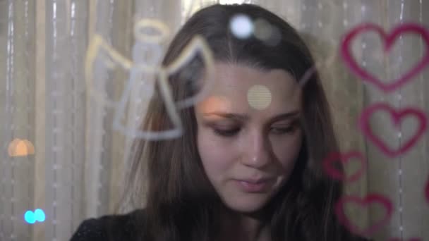 Красивая девушка рисует сердце и ангела на стекле — стоковое видео