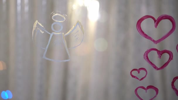 Όμορφη κοπέλα ζωγραφίζει καρδιά και άγγελο στο γυαλί — Αρχείο Βίντεο