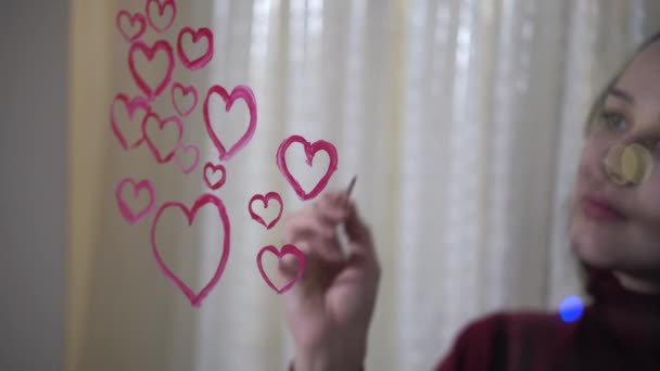 Beautiful girl paints a heart on glass — ストック動画