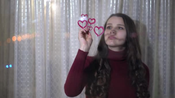 Schönes Mädchen malt ein Herz auf Glas — Stockvideo