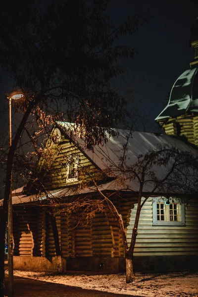 Orthodox tree Russian church covered with snow. Wooden church with lights and illuminated crosses on tops in christmas eve. Christmas evening near christian church, spiritual moment.