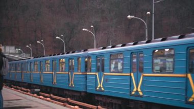 Mavi metro treni Kiev 'deki geniş Dinyeper Nehri' nin karşısındaki köprüdeki yer istasyonundan ayrılıyor..