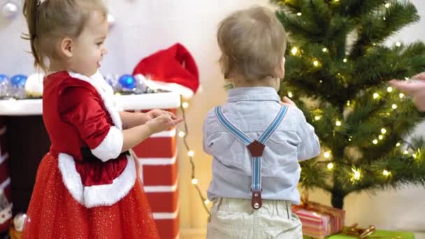 Dítě a těhotná maminka pověsit červený míč hračka na vánoční stromek. Šťastné dětství. dítě a matka zdobí strom s vánočními míčky. malé dítě a rodič hrají u vánočního stromečku. — Stock video