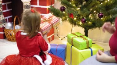 Bebek ve hamile bir anne Noel ağacına kırmızı top oyuncağı asıyor. Mutlu çocukluk kavramı. Çocuk ve anne Noel toplarıyla ağacı süslerler. Küçük çocuk ve bir ebeveyn Noel ağacının yanında oynuyorlar..