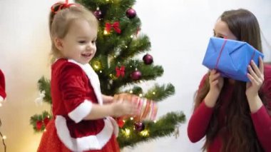 Bebek ve hamile bir anne Noel ağacına kırmızı top oyuncağı asıyor. Mutlu çocukluk kavramı. Çocuk ve anne Noel toplarıyla ağacı süslerler. Küçük çocuk ve bir ebeveyn Noel ağacının yanında oynuyorlar..