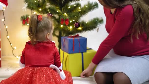 Dítě a těhotná maminka pověsit červený míč hračka na vánoční stromek. Šťastné dětství. dítě a matka zdobí strom s vánočními míčky. malé dítě a rodič hrají u vánočního stromečku. — Stock video
