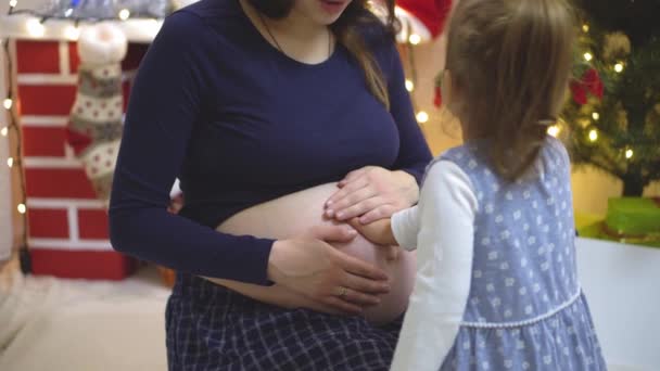 Twee kinderen betast luisteren en kus de buik van een zwangere moeder — Stockvideo