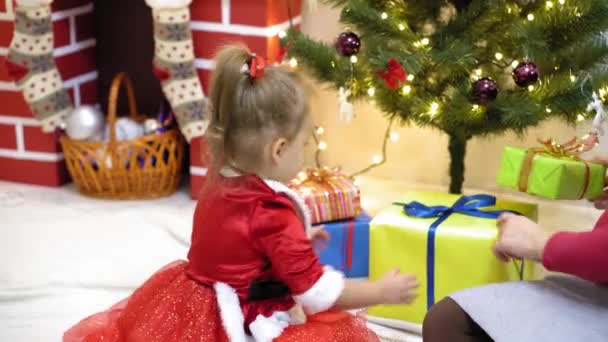 Baby och pregnan mamma hänga röd boll leksak på julgran. Glad barndom. barn och mor dekorera trädet med julbollar. litet barn och en förälder leker vid julgranen. — Stockvideo