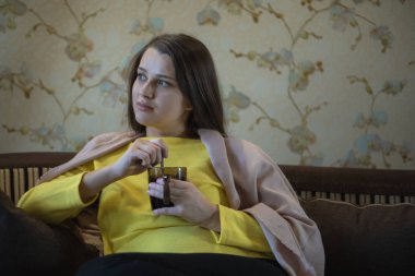 Hoş ve düşünceli bir kızın resmi kanepede oturur ve çay içer. Onun omuzlarında kahverengi battaniye var. Kadın üşümüş. Pencerede sürtüyor.