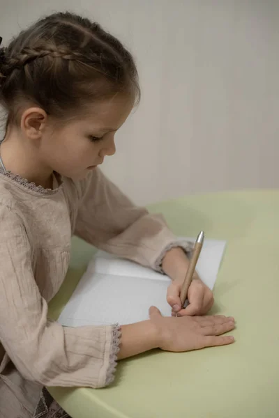 Ένα μελαχρινό ξανθό κορίτσι με μπεζ φόρεμα διαβάζει. — Φωτογραφία Αρχείου