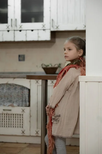 Une fille blonde foncée dans une robe beige et une écharpe colorée qui pend de son épaule dans la cuisine — Photo