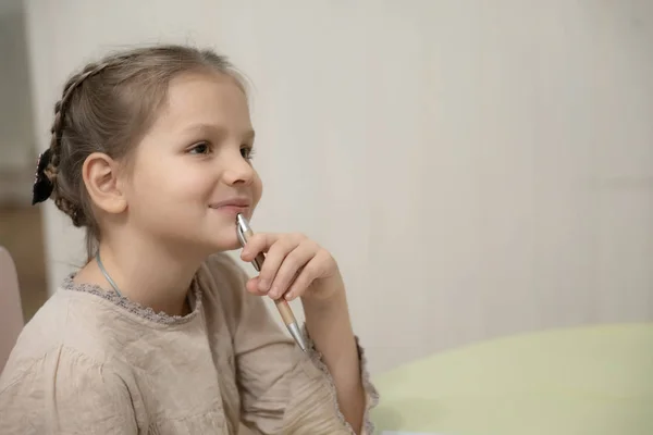 Een donker blond meisje in een beige jurk doet huiswerk — Stockfoto