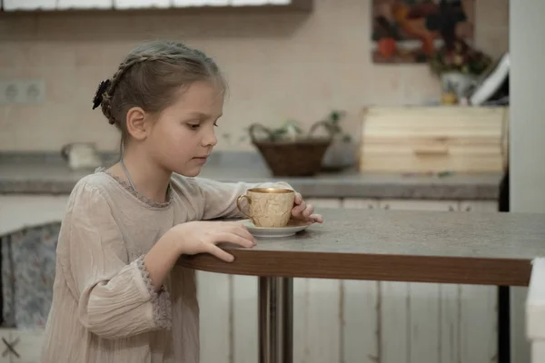 Chica rubia oscura en un vestido beige bebe té en la cocina — Foto de Stock